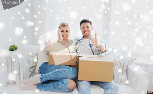 Image of happy couple with boxes showing thumbs up at home