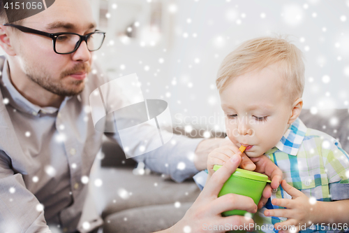 Image of father and son drinking from cup at home