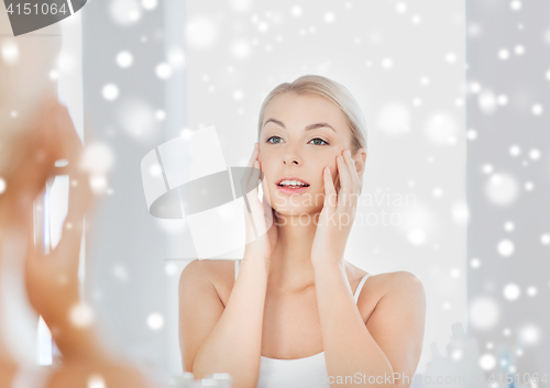 Image of happy young woman looking to mirror at bathroom