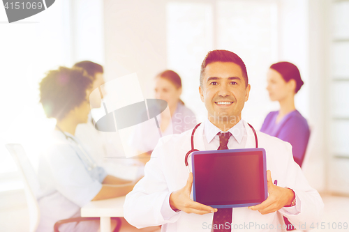 Image of happy doctor with tablet pc over team at clinic