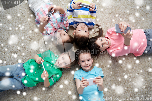 Image of happy children with smartphones lying on floor