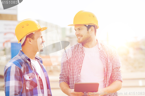 Image of smiling builders with tablet pc outdoors