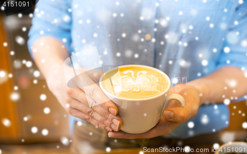 Image of close up of hands with latte art in coffee cup