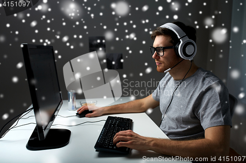 Image of man in headset playing computer video game at home