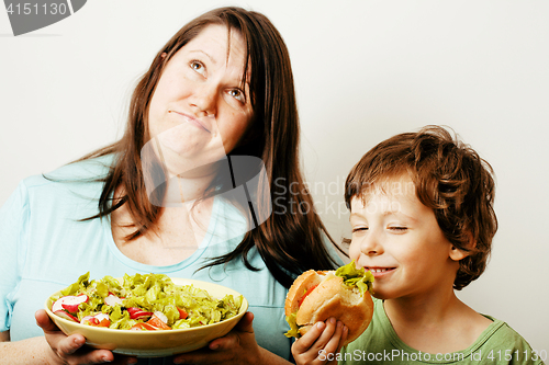 Image of mature woman holding salad and little cute boy with hamburger te