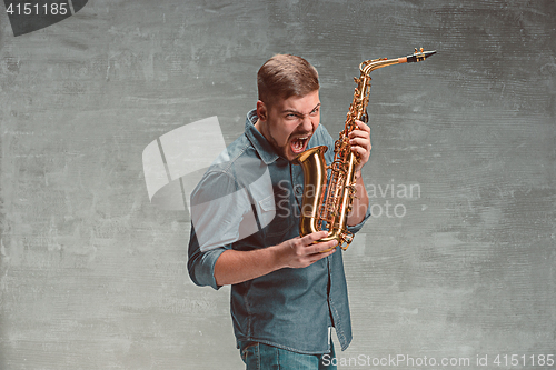 Image of Happy saxophonist with sax over gray background