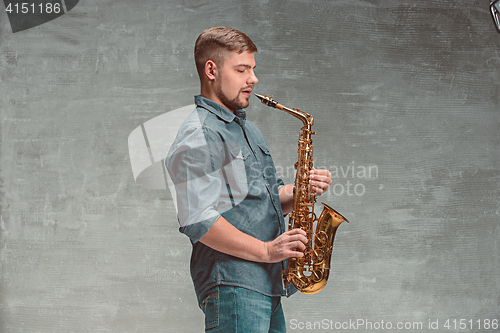 Image of Happy saxophonist with sax over gray background