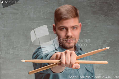 Image of Man holding two drumsticks over gray background