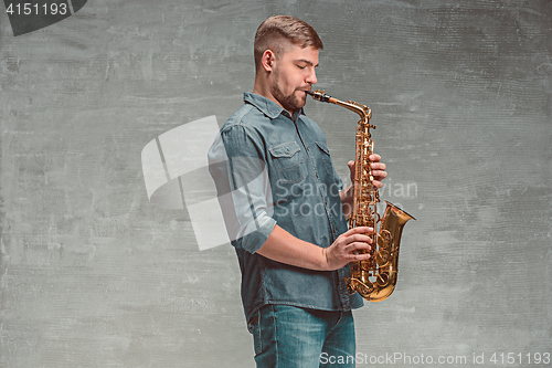 Image of Happy saxophonist playing music on sax over gray background