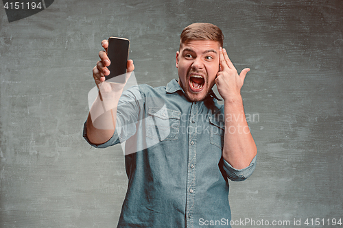 Image of The young smiling caucasian businessman on gray background with phone