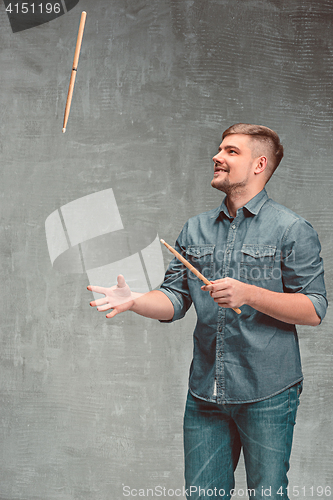 Image of Man holding two drumsticks over gray background