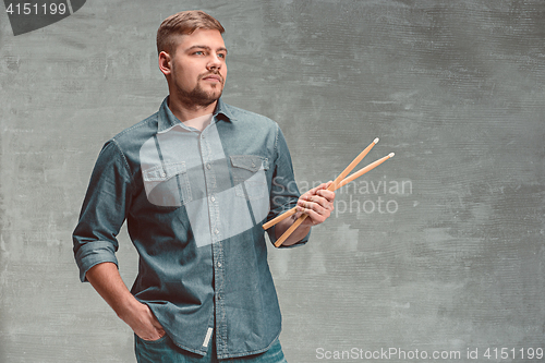 Image of Man holding two drumsticks over gray background