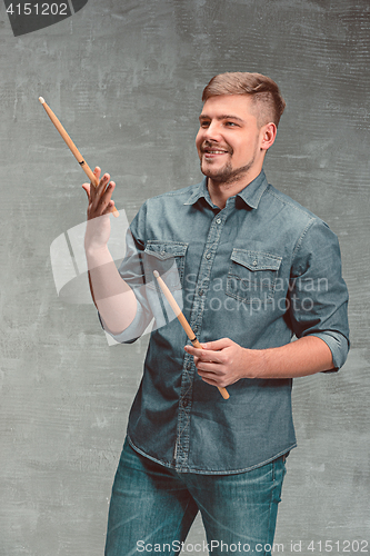 Image of Man holding two drumsticks over gray background