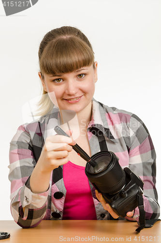 Image of Photographer cleans front of the lens on the camera and looked into the frame