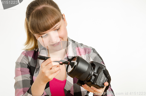 Image of Photographer brush cleans the front of the lens on the camera