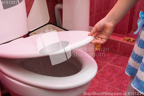 Image of Child\'s hand lifts the lid of the toilet, close-up