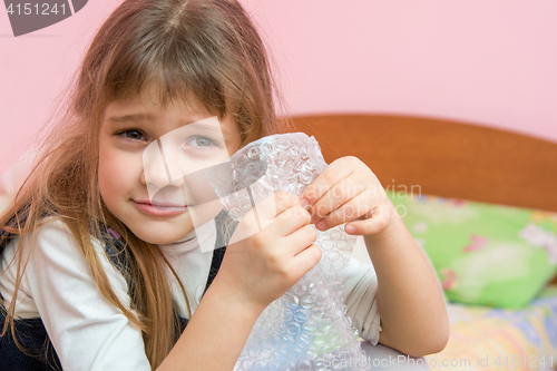 Image of Five-year girl listens to burst like bubbles on the packaging bag