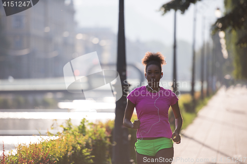 Image of african american woman jogging in the city