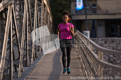 Image of african american woman running across the bridge