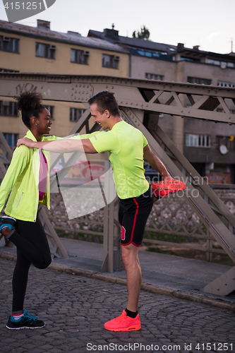 Image of jogging couple warming up and stretching in the city