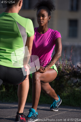 Image of jogging couple warming up and stretching in the city