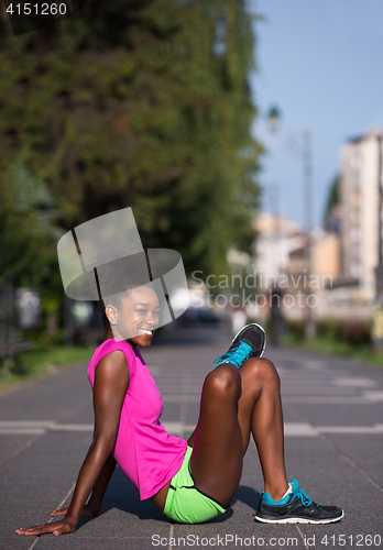 Image of sporty young african american woman stretching outdoors