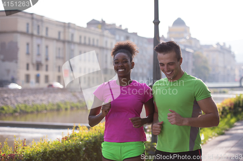 Image of young multiethnic couple jogging in the city