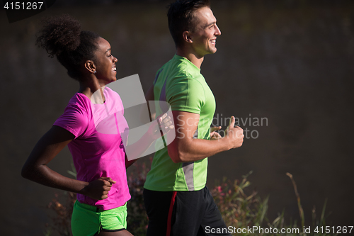 Image of young smiling multiethnic couple jogging in the city