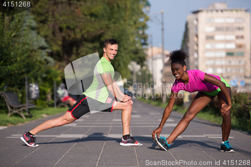 Image of jogging couple warming up and stretching in the city