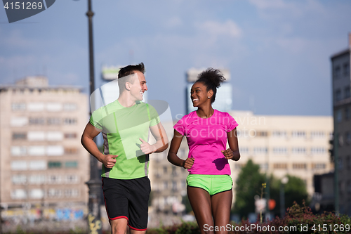 Image of young smiling multiethnic couple jogging in the city