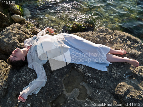 Image of Young Lady Ethic Dress Lying on Sea Rock