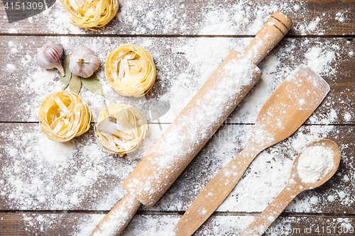 Image of Wooden rolling pin with flour and pasta