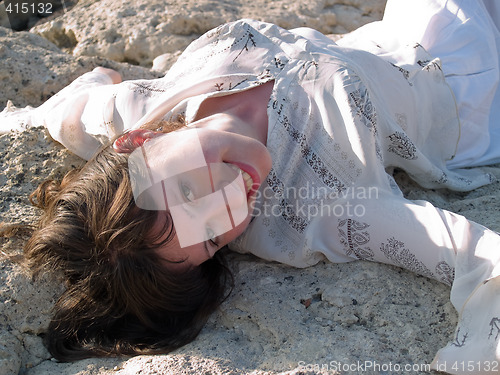 Image of Portrait of Smiling Lady Ethic Dress Lying on Stone