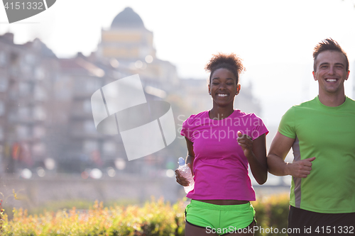 Image of young multiethnic couple jogging in the city