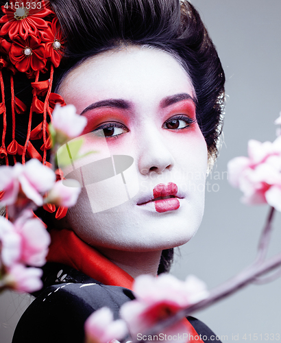 Image of young pretty geisha in black kimono among sakura, asian ethno