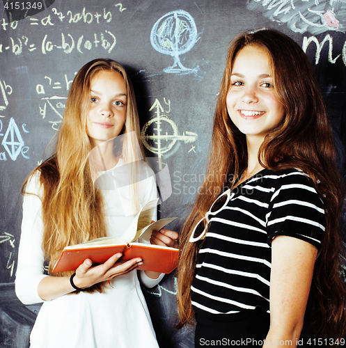 Image of back to school after summer vacations, two teen real girls in classroom with blackboard painted together, lifestyle real people concept