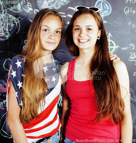 Image of back to school after summer vacations, two teen real girls in classroom with blackboard painted together, lifestyle real people concept