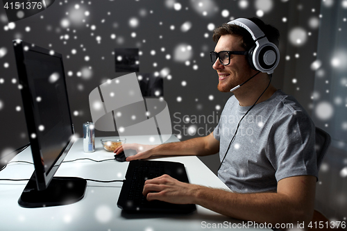 Image of man in headset playing computer video game at home