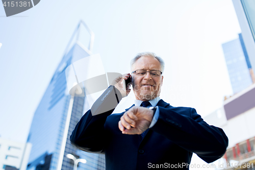 Image of senior businessman calling on smartphone in city