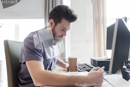 Image of creative male office worker with coffee writing