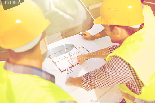 Image of close up of builders with blueprint on car hood