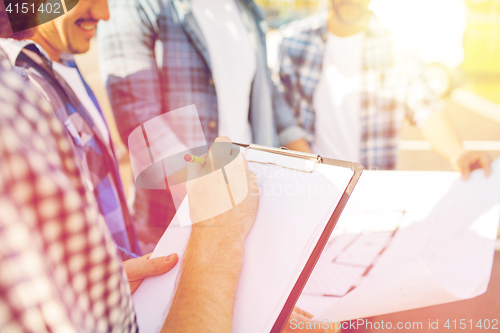 Image of close up of builders with clipboard and blueprint