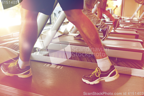 Image of close up of men legs walking on treadmills in gym