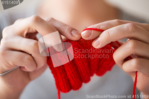 Image of close up of hands knitting with needles and yarn