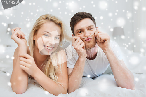 Image of happy couple lying in bed at home