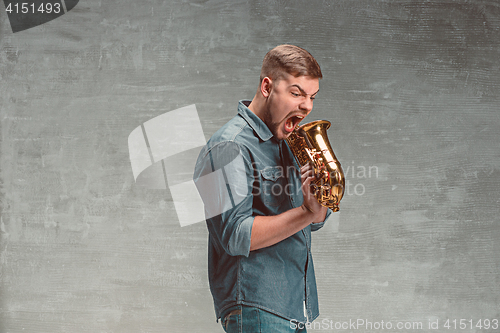 Image of Happy saxophonist with sax over gray background