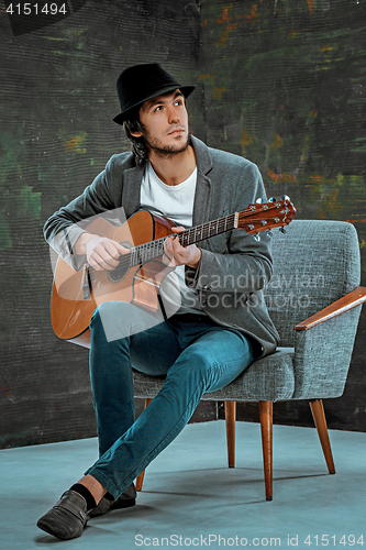 Image of Cool guy with hat playing guitar on gray background