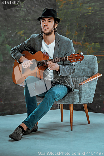 Image of Cool guy with hat playing guitar on gray background