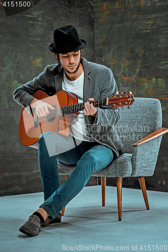 Image of Cool guy with hat playing guitar on gray background