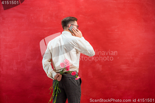 Image of Man holding bouquet of carnations behind back